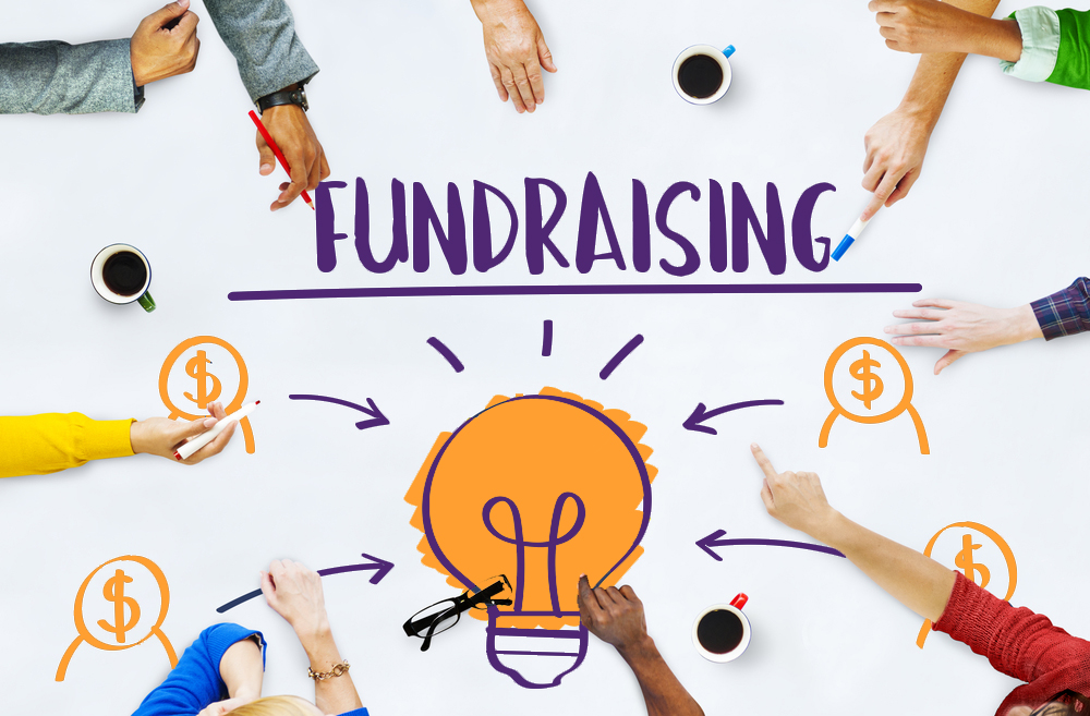 A whiteboard with the word fundraising above a lightbulb surrounded arrows and circled dollar signs. Hands reach into the image with markers and pens as if to share ideas