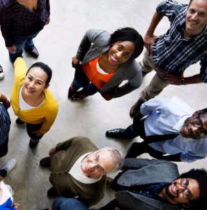 A diverse group of people standing on a white floor looking up at the camera