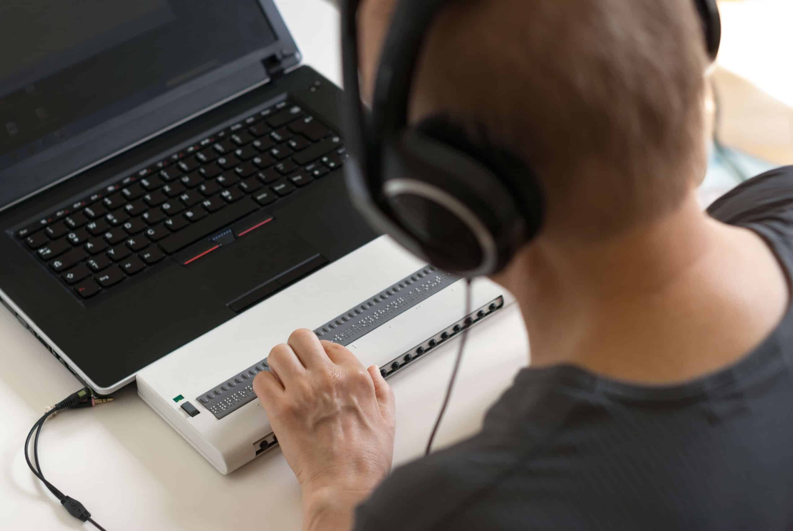 A person uses headphones and a Braille keyboard