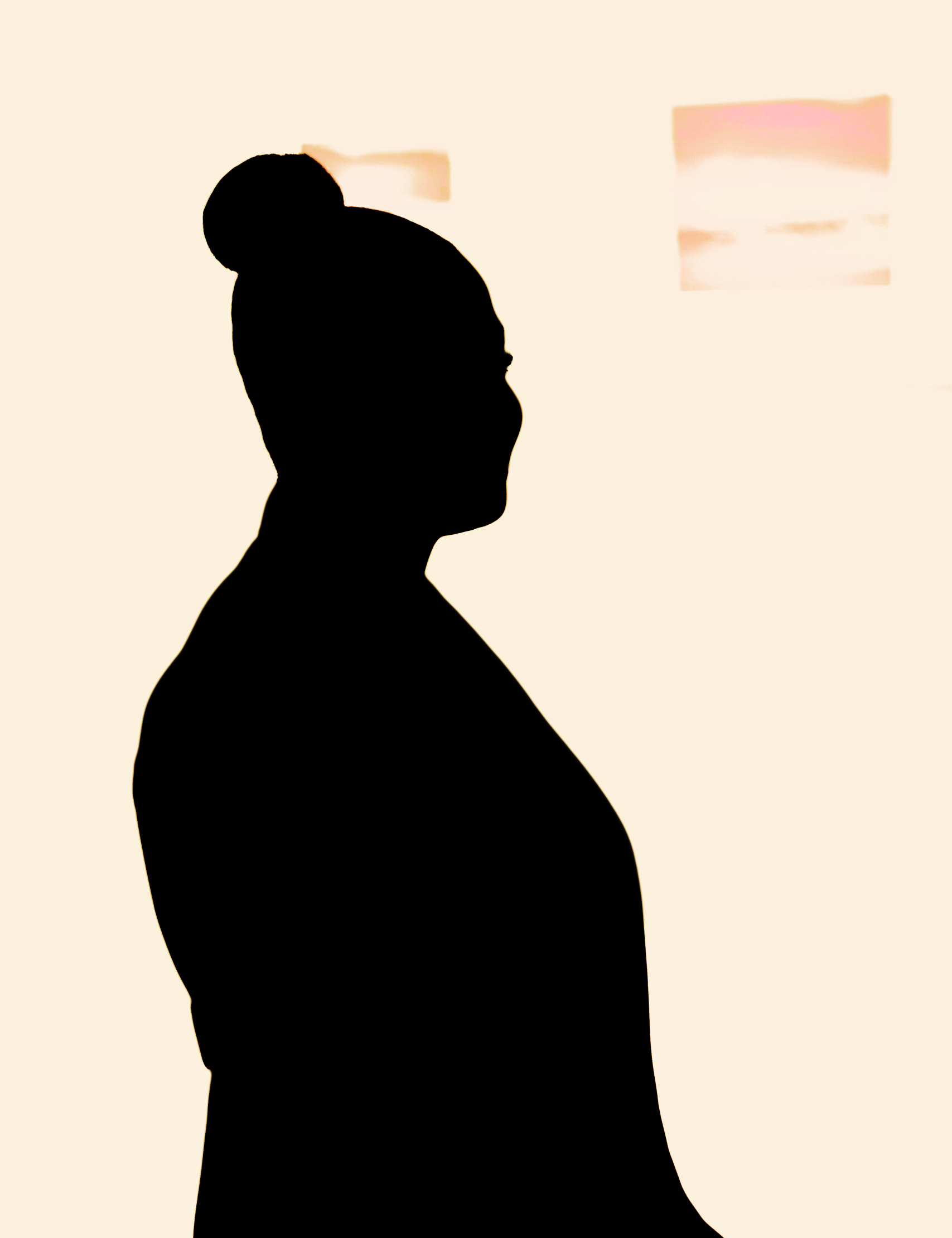 a silhouette of a person with their hair in a bun on top of their head against a peach-colored background